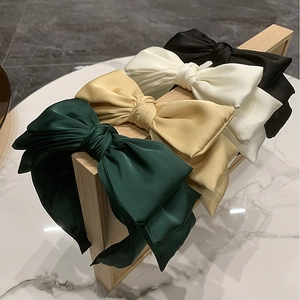 Close-up of four layered satin bow headbands in green, gold, beige and black