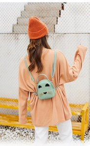 Outdoor view of a mint green cat-shaped mini backpack with metal whiskers and ears