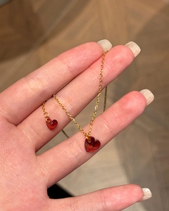 Detailed shot of a red heart-shaped crystal pendant with a sleek gold-colored metal chain