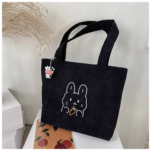 Detail of black corduroy tote bag featuring rabbit embroidery and a cute cow pendant