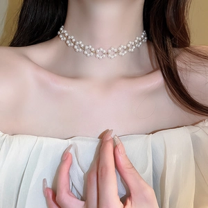Détail du collier ras du cou en perles blanches en forme de fleur avec métal doré