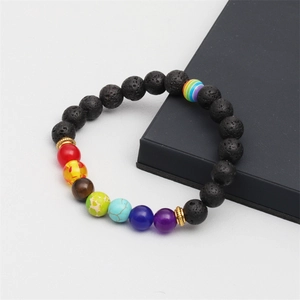 Gros plan sur les perles de chakra colorées et les pierres de lave noires du bracelet