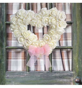 Détail d'une couronne en forme de cœur avec roses blanches et un nœud rose sur fenêtre rétro
