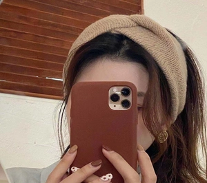 Detail of knitted cross-knot headband in camel beige, worn by model for autumn style