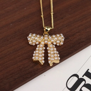 Elegant gold necklace featuring a classic bow pendant set with white pearls on wood