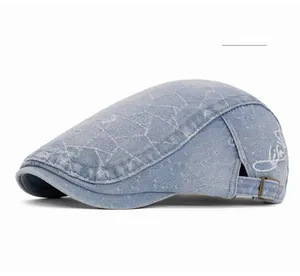 Detail of light blue denim ivy cap with white geometric embroidery and bronze buckle