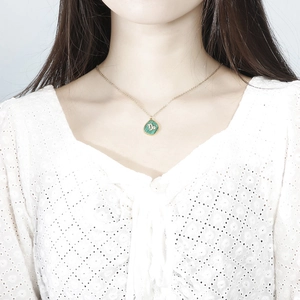 Detail of Capricorn zodiac necklace with green malachite pendant on model's neckline
