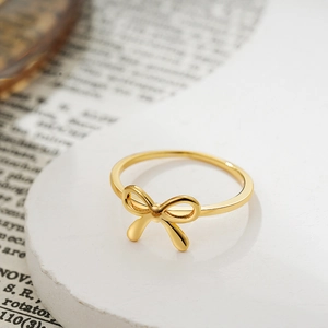 Macro shot of 18K gold bow-shaped ring on a stone base with soft lighting