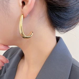 Close-up of elegant gold C-shaped drop earrings worn by a model in a luxury style