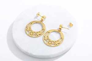 Detailed view of gold star and moon drop earrings with clear gems on marble base