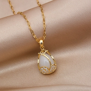 Elegant gold tulip necklace with white cat eye stone on champagne silk background