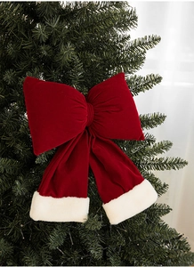 Close-up of red velvet Christmas bow with white plush trim on a green Christmas tree