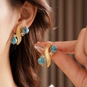 Vintage gold leaf earrings with turquoise stones and white zircons worn by a model