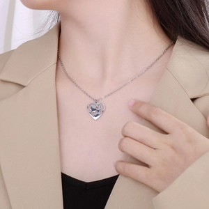 Close-up of mother and child silhouette inside heart pendant on silver necklace