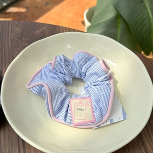 Blue and white striped scrunchie with pink trim and NOTES tag on a white ceramic plate