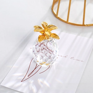 Macro shot of faceted crystal pineapple with metallic gold leaves on marble base
