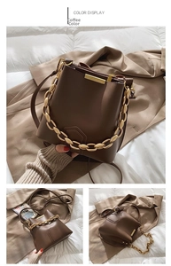 Detail of a brown bucket bag with a chunky gold chain and smooth leather texture