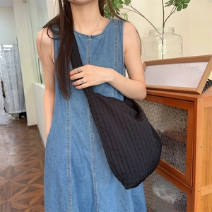 Détail du sac à bandoulière noir plissé texturé avec large sangle sur un mannequin