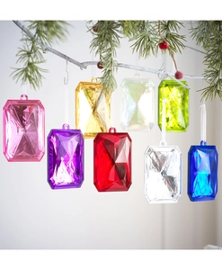 Macro view of multi-colored faceted acrylic gem ornaments hanging on a pine tree branch