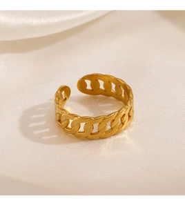 Macro detail of golden chain link ring featuring polished finish on white satin background