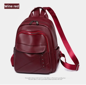 Detail shot of a wine red PU leather backpack with side rivet accents and lychee texture