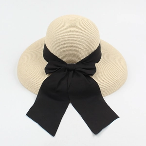 Detail of the woven straw hat featuring a large black ribbon bow for sun protection