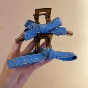Detailed close-up of blue denim bow hair claw clips with sparkling mini rhinestones