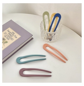 Detail shot of six colorful U-shaped resin hair pins in soft candy colors on a book