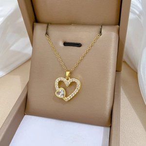 Gros plan du pendentif double cœur doré serti de zircons sur un coussin en satin