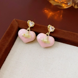 Close-up of pink heart earrings with gold needles and sparkling crystal accents