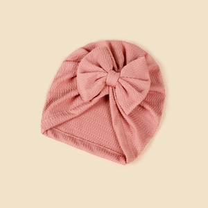 Detail of pink waffle knit baby turban hat featuring a large decorative bow