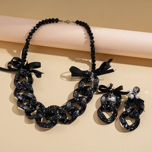 Detail of chunky acrylic chain necklace with ink-splash pattern and ribbon bow