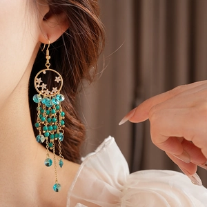 Détail de boucles d'oreilles vintage en or avec pompons en cristal bleu et perles rondes