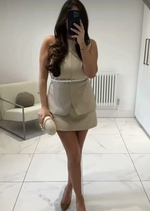 Detail view of beige sleeveless commute dress with a thin white belt and clutch bag