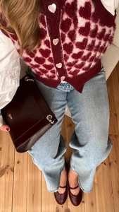 Vue à plat d'un cardigan en mohair à cœurs avec un jean bleu et des chaussures rouges
