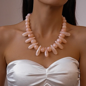 Detailed close-up of chunky pink acrylic beaded necklace with teardrop resin charms
