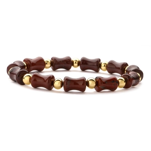 Detail of beaded bamboo-style bracelet with reddish-brown drum beads and gold accents