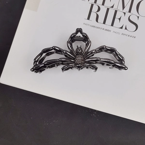 Detailed top view of a large black metal spider hair claw clip on a white decorative card