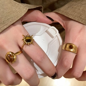 Detailed view of three vintage gold rings with brown stones on hand with warm tones