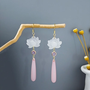 Detail of pink lotus flower earrings hanging on a branch with long tassel pendants