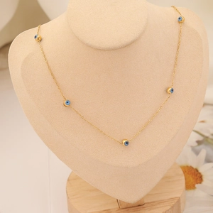 Collier doré avec perles d'oeil bleu sur un présentoir de cou de couleur chair