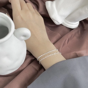 Détail du bracelet double couche en argent sur poignet avec un fond en satin élégant