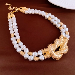 Macro detail of luxury double-strand baroque pearl necklace with gold knotted pendant