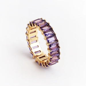 Détail d'une bague dorée avec zircons violets à coupe rectangulaire et serti à griffes