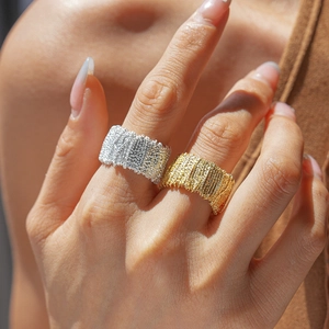 Macro shot of gold and silver textured woven wide band rings on a model's hand