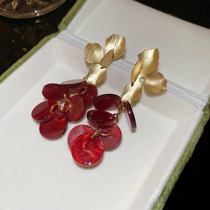 Detailed macro view of vintage red acrylic disc tassel earrings with golden floral petals