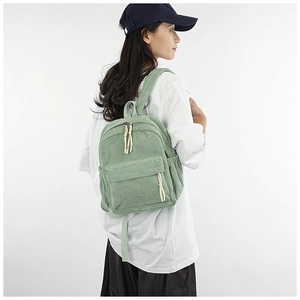 Detailed close-up of green corduroy backpack texture and straps on a model back