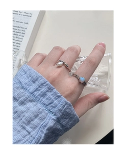 Dettaglio di anelli in argento S925 con opale a cuore e perla sulla mano di donna