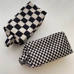 Top view of two checkerboard velvet makeup bags with textured fabric and side handles