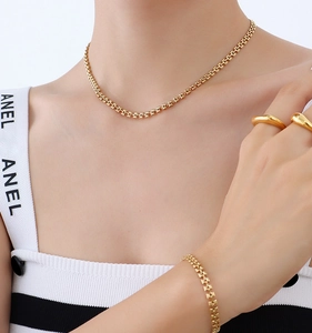Détail de l'ensemble collier à chaîne géométrique dorée, bracelet et bagues assortis